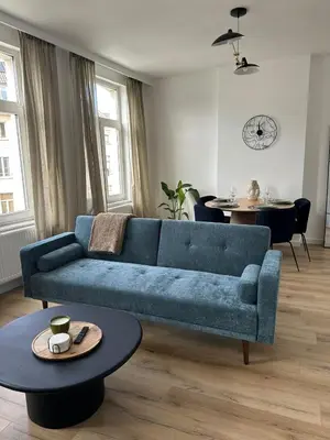 a living room with a blue couch and a table at 2- Nid lumineux 1 chambres au coeur d'Ixelles in Brussels