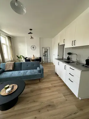 a living room with a blue couch and a kitchen at 2- Nid lumineux 1 chambres au coeur d'Ixelles in Brussels