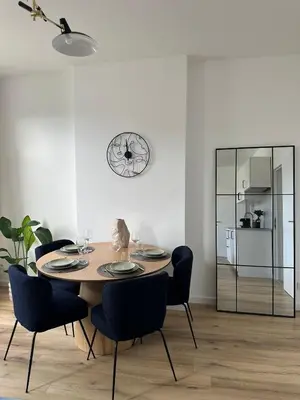 a dining room table with chairs and a clock on the wall at 2- Nid lumineux 1 chambres au coeur d'Ixelles in Brussels