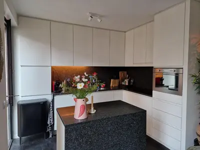 a kitchen with white cabinets and a vase of flowers on a counter at Appartement historisch centrum Antwerpen in Antwerp