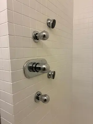 a shower with silver fixtures on a white tiled wall at Appartement historisch centrum Antwerpen in Antwerp