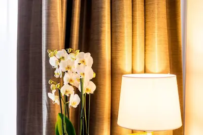 a lamp and flowers in front of a curtain at Tower Hotel Aalst in Aalst