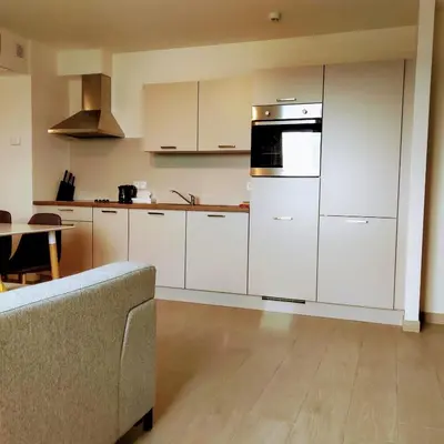 a kitchen with white cabinets and a table and a couch at Tower Hotel Aalst in Aalst