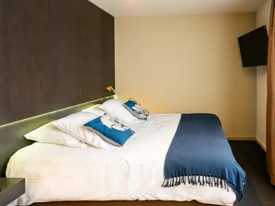 a bedroom with a bed with blue and white pillows at Tower Hotel Aalst in Aalst