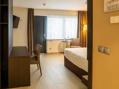a hotel room with a bed and a desk and a table at Tower Hotel Aalst in Aalst