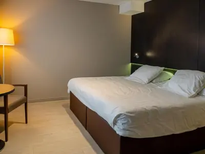 a bedroom with a bed with a black headboard and a table at Tower Hotel Aalst in Aalst