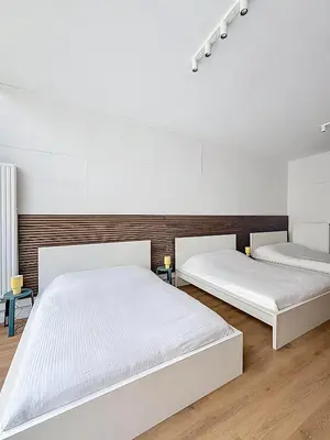 two beds in a room with white walls and wooden floors at Central Spot - Louise in Brussels
