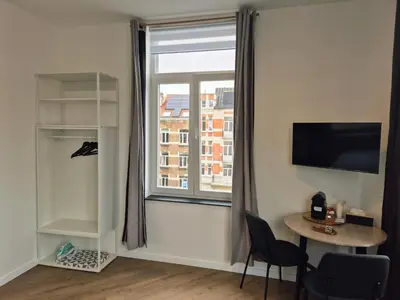 a room with a large window and a table and chair at Studios - European Quarter in Brussels