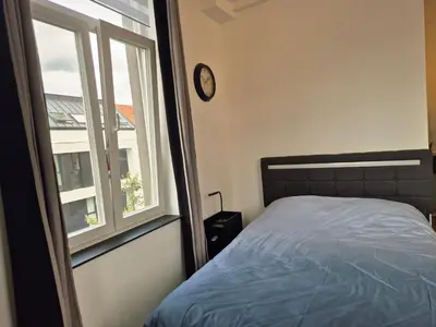 a bedroom with a bed and a window with a clock at Studios - European Quarter in Brussels