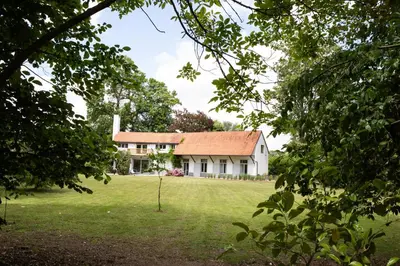 a large white house with a red roof at Le Paddock by Ernesst in Lubbeek