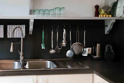 a kitchen sink with utensils hanging on a wall at Le Paddock by Ernesst in Lubbeek