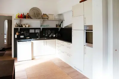 a white kitchen with black counters and white cabinets at Le Paddock by Ernesst in Lubbeek