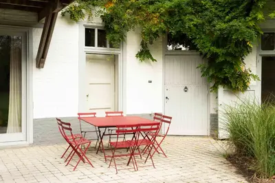 a red table and chairs in front of a house at Le Paddock by Ernesst in Lubbeek
