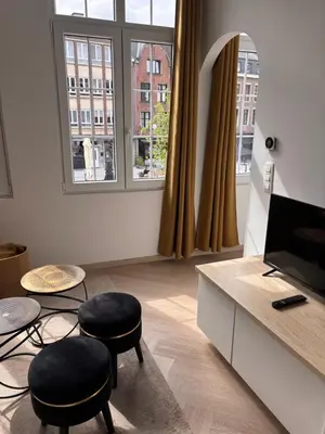 a living room with two stools and a desk with two windows at Studio Miravelle in Antwerp