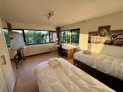 a bedroom with two beds and a desk and windows at 3BR Villa with Big Garden, Ping-Pong, Cinema, Bath in Ghent