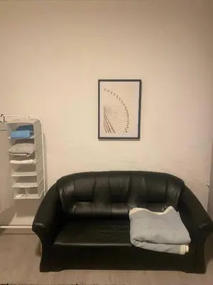 a black leather couch in a room with a picture at Big beautiful appartement in center of Antwerpen in Antwerp