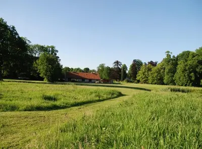 a field of grass with a house in the background at De Middenblijk in Turnhout