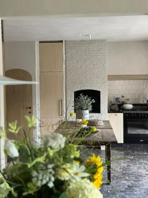 a kitchen with a table with flowers in the foreground at De Middenblijk in Turnhout