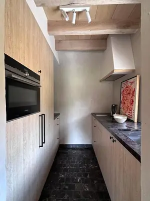 a small kitchen with a counter and a tv on the wall at Gastenverblijf De Middenblijk in Turnhout
