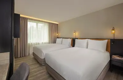 a hotel room with two beds and a chair at Courtyard by Marriott Ghent in Ghent