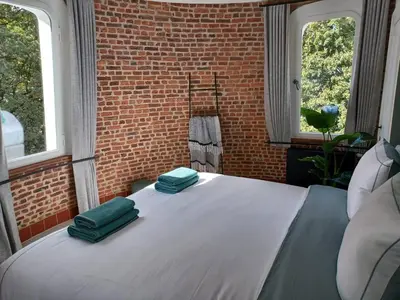 a bed in a room with two green pillows on it at De Zwarte Molen - erfgoedlogie in het groen in Lille