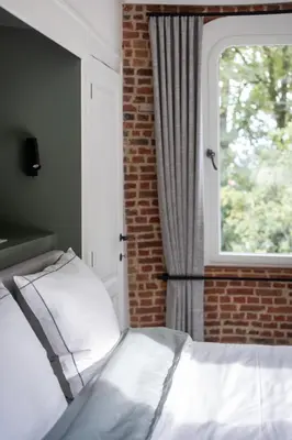 a bedroom with a bed and a window at De Zwarte Molen - erfgoedlogie in het groen in Lille
