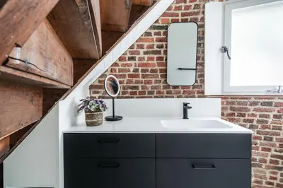 a bathroom with a sink and a brick wall at De Zwarte Molen - erfgoedlogie in het groen in Lille