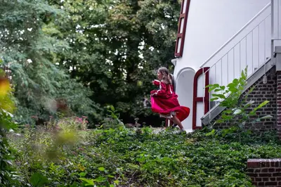 a woman in a red dress walking on a building at De Zwarte Molen - erfgoedlogie in het groen in Lille
