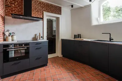 a kitchen with black cabinets and a tile floor at De Zwarte Molen - erfgoedlogie in het groen in Lille