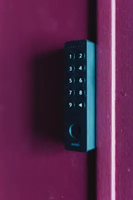 a black remote control sitting on a pink door at Kouter House in Ghent