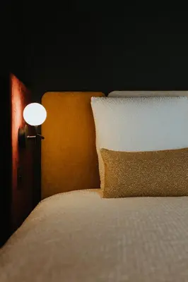 a bed with a white pillow and a lamp on it at Kouter House in Ghent