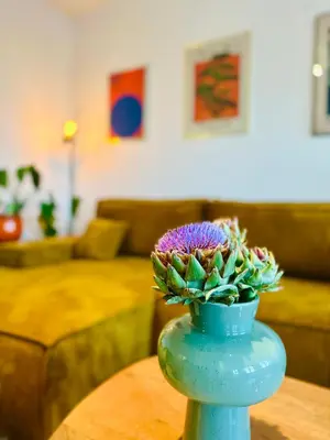 a blue vase with a purple plant on a table at Antwerp City Nest in Antwerp