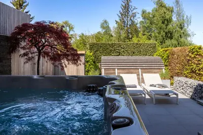 a hot tub in a backyard with a bench at Relax Ohm in Zottegem