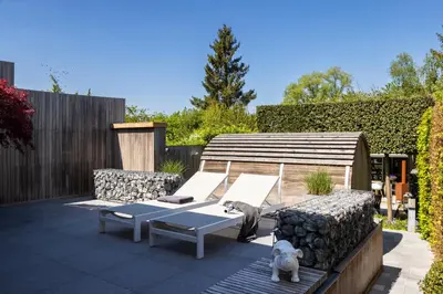 a patio with two chairs and a table and a dog at Relax Ohm in Zottegem
