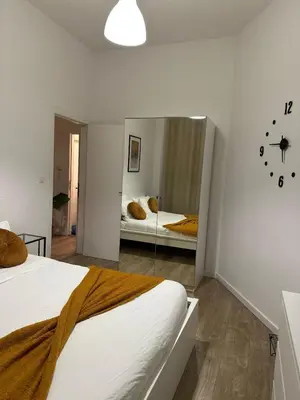 a bedroom with a mirror and a bed and a clock at A little love nest in Brussels