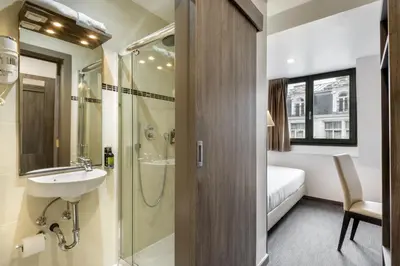 a bathroom with a sink and a shower and a bed at Dansaert Hotel in Brussels