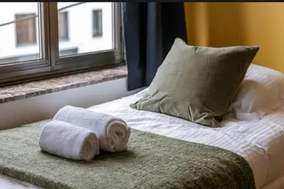 a bed with two towels and a pillow and a window at Sweet home in Ghent