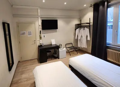 a bedroom with two beds and a desk and a table at Albert 2 - Basic Room in Mechelen