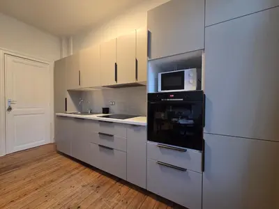 a kitchen with white cabinets and a microwave at La Suite Eleonore in Brussels