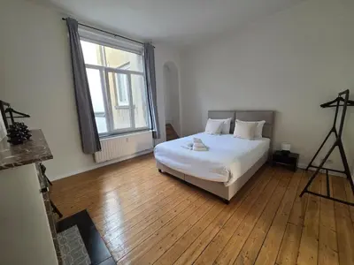 a bedroom with a white bed and a large window at La Suite Eleonore in Brussels