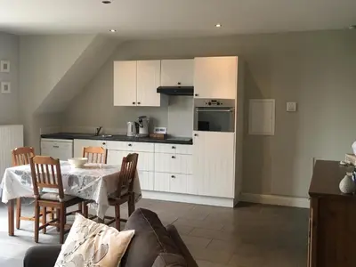 a kitchen with white cabinets and a table and chairs at Guesthouse De Middelvelden in Arendonk