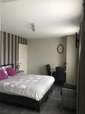 a bedroom with a bed and a desk and a clock at Guesthouse De Middelvelden in Arendonk