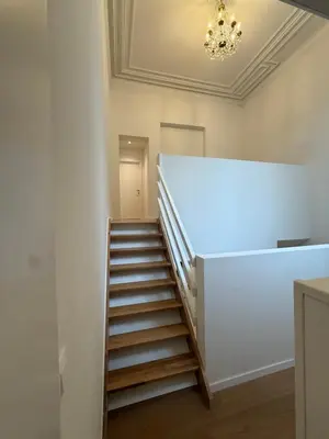 a staircase in a room with a white wall and a chandelier at The Gallery Saint-Gilles in Brussels