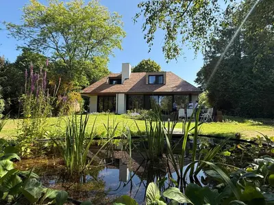 a house with a pond in front of it at B&Biotope in Heusden