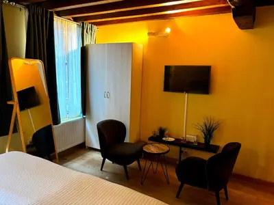 a hotel room with a bed and chairs and a television at Family Heritage Grand Place in Brussels