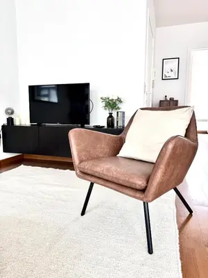 a brown chair in a living room with a tv at Wonderful apartment in Sablon in Brussels