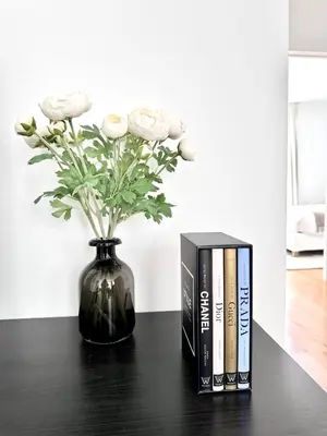 a black book next to a vase with flowers at Wonderful apartment in Sablon in Brussels