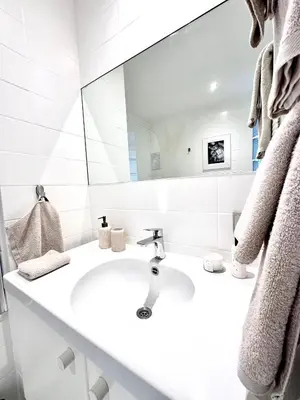 a white bathroom with a sink and a mirror at Wonderful apartment in Sablon in Brussels