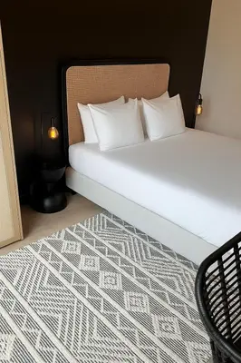 a bed with white pillows and a black and white carpet at Cosy 2-Room Apartment for 4 Guests near Gent Sint-Pieters Station, and Close to the City Centre in Ghent