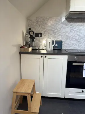 a kitchen with white cabinets and a wooden stool at littoral in Brussels
